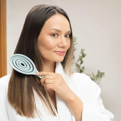 Brosse cheveux bouclés Femme aux cheveux longs et lisses utilisant une brosse démêlante douceur.